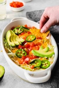 a person dipping tortilla chips into a dish of salsa.