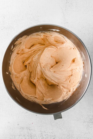 a bowl of orange icing on a white background.