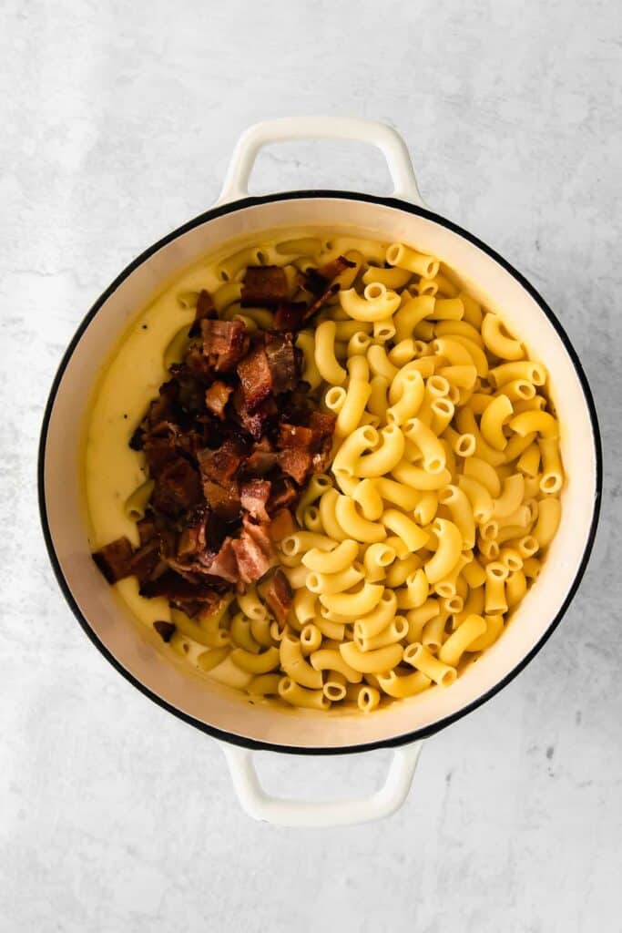 Macaroni noodles, bacon, and a cheese sauce in a Dutch oven.