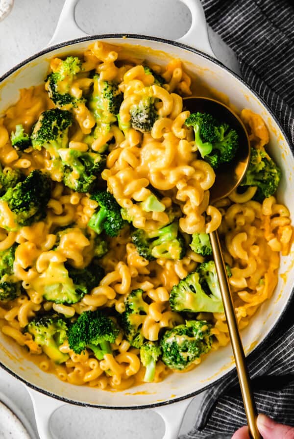 a bowl of macaroni and broccoli with a spoon.