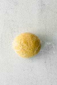 A homemade ball of pasta in a plastic bag on a white surface.