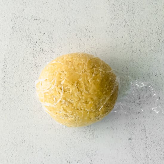 A homemade ball of pasta in a plastic bag on a white surface.