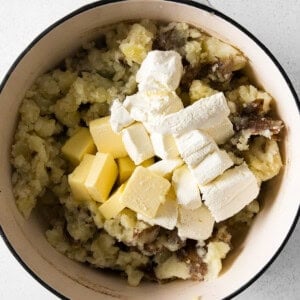 mashed potatoes and cheese in a pot on a white background.