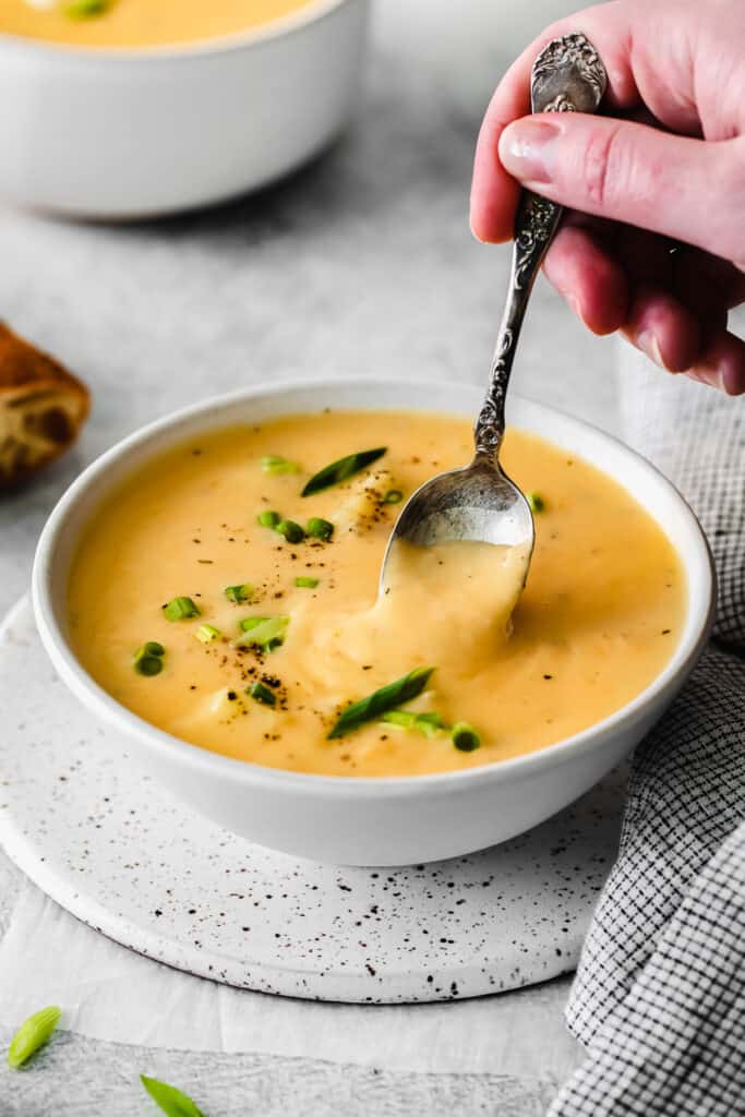 a spoon in cheesy potato soup in a bowl.