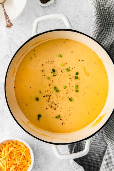 Cheesy potato soup served in a simmering white pot.