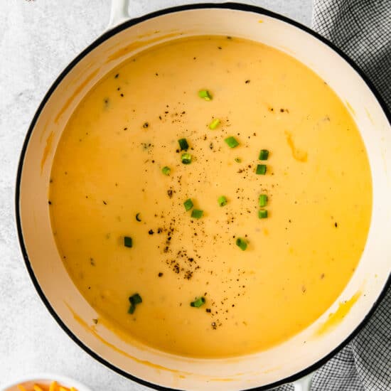 Cheesy potato soup served in a simmering white pot.