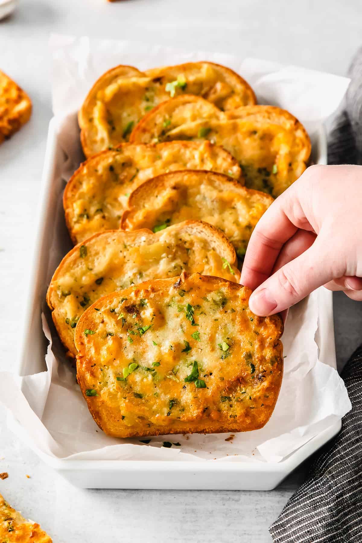 A hand grabbing a piece of Texas toast. 