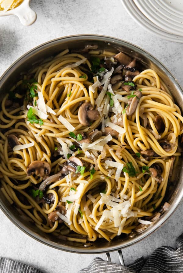 a pan of spaghetti with mushrooms and parmesan.