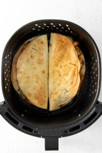 an air fryer with two quesadillas in it.