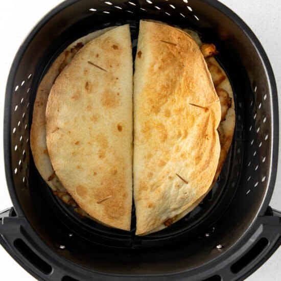 an air fryer with two quesadillas in it.