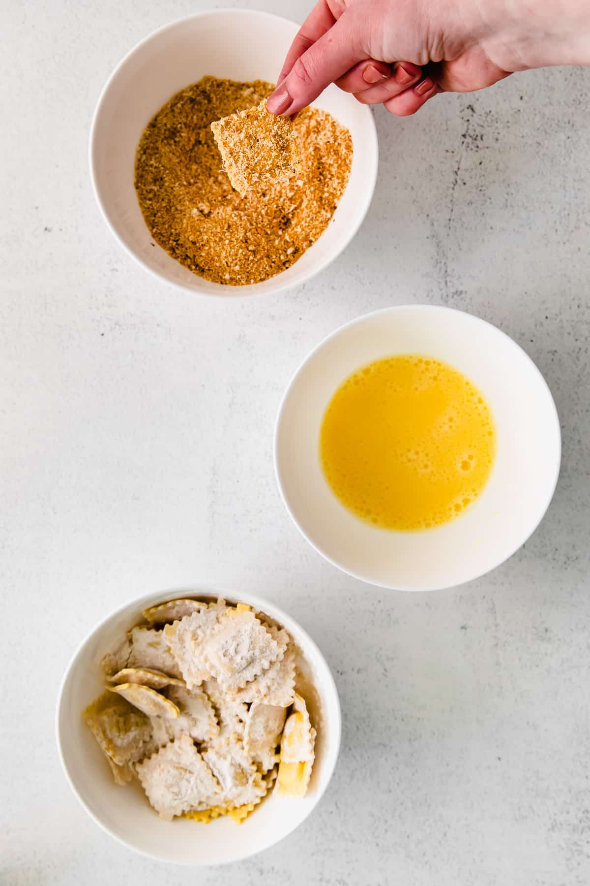 Dipping ravioli into a breadcrumb and parmesan mixture. 