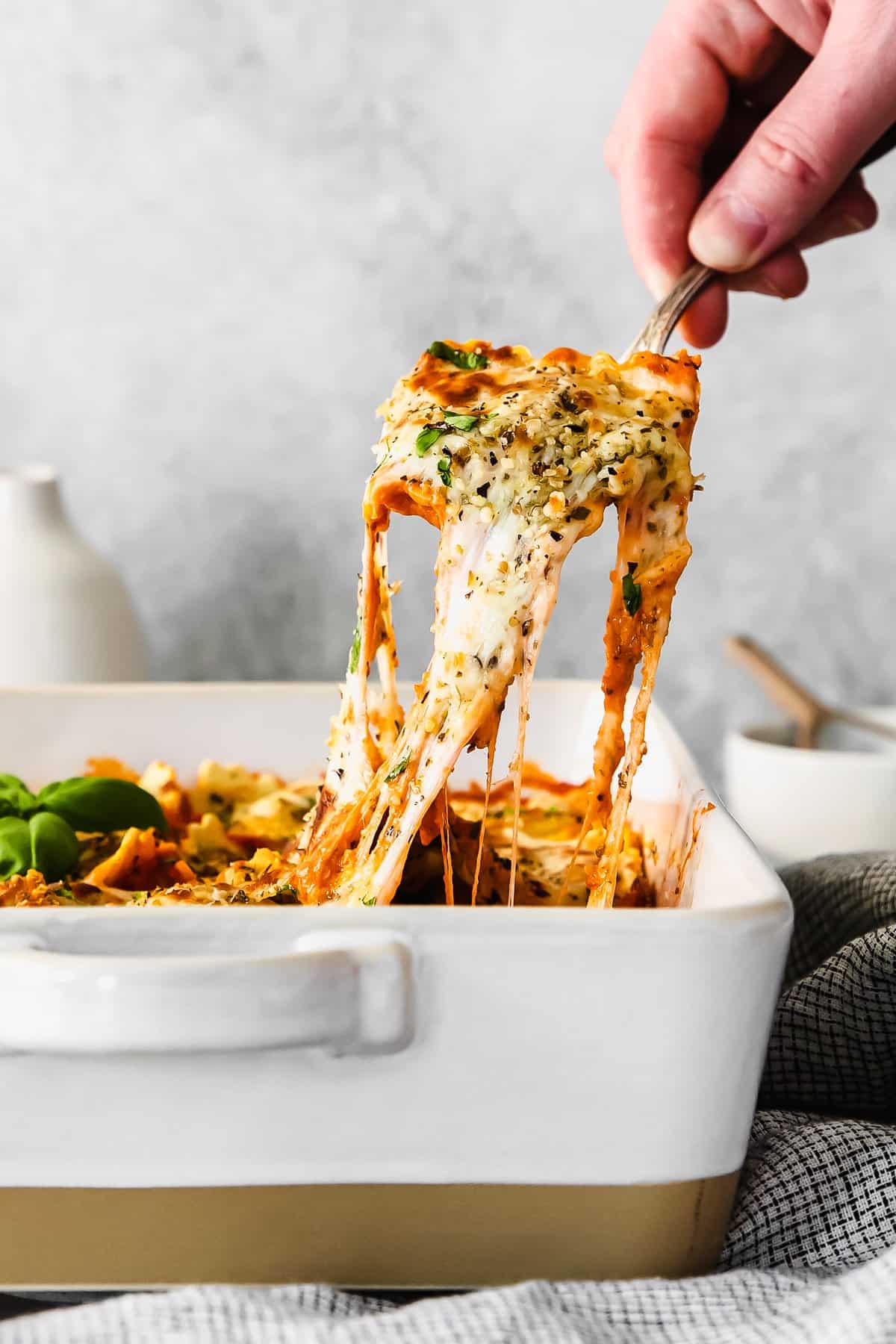 Scooping ravioli out of a casserole dish. 