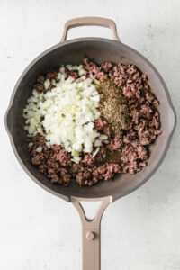 ground beef and onions in a frying pan.