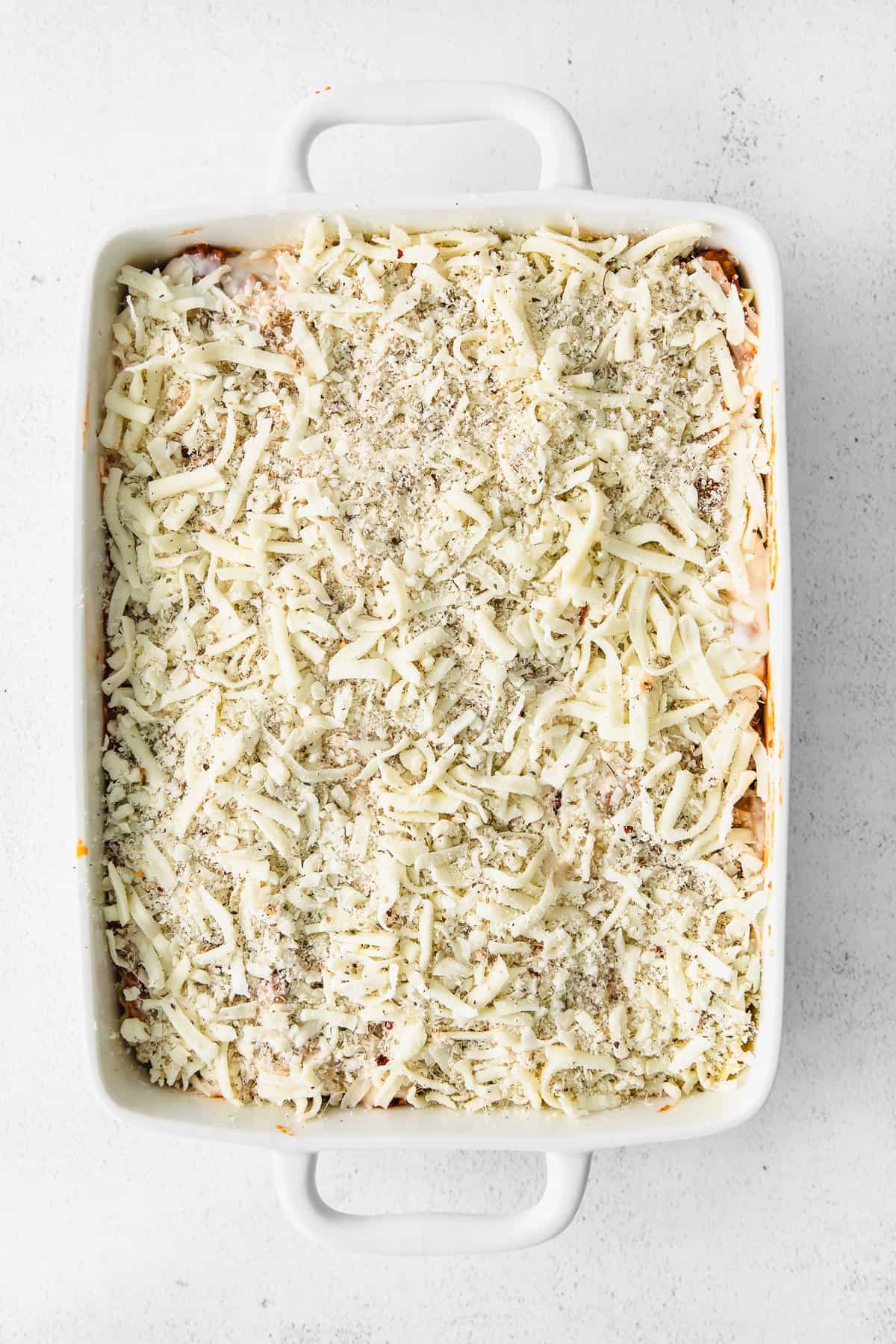 Lasagna covered in shredded cheese in a casserole dish.