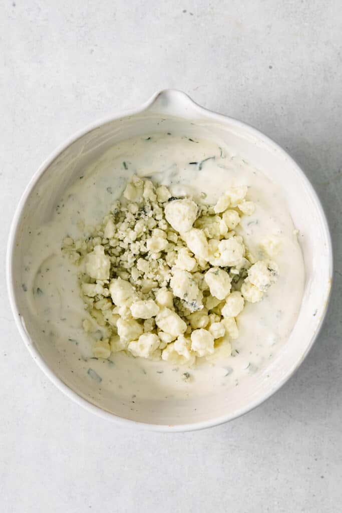 blue cheese dip and dressing with blue cheese crumbles in a bowl