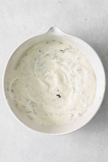 a white bowl with a white sauce on it.