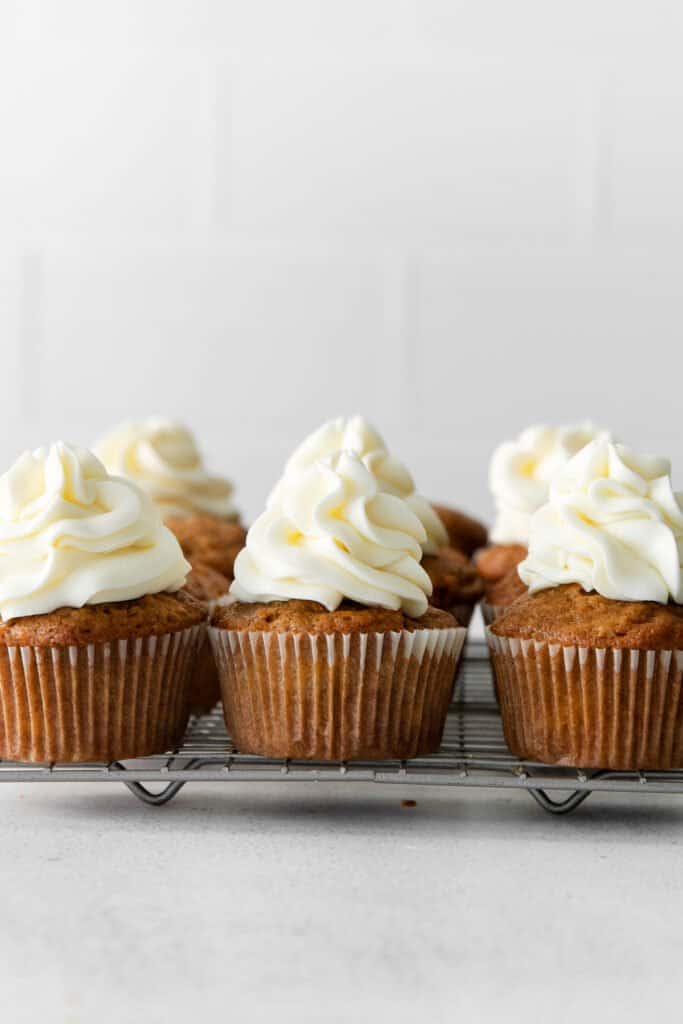 Frosted carrot cake cupcakes on a cooling rack. 