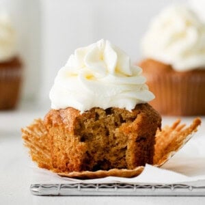 A carrot cake cupcake with a bite taken out of it.