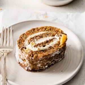 a slice of carrot roll on a plate with a fork.