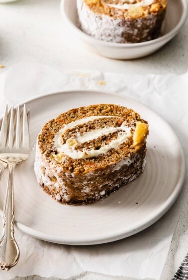 a slice of carrot roll on a plate with a fork.