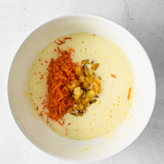 a bowl of soup with carrots and nuts in it.