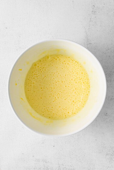 a bowl of yellow liquid on a white surface.