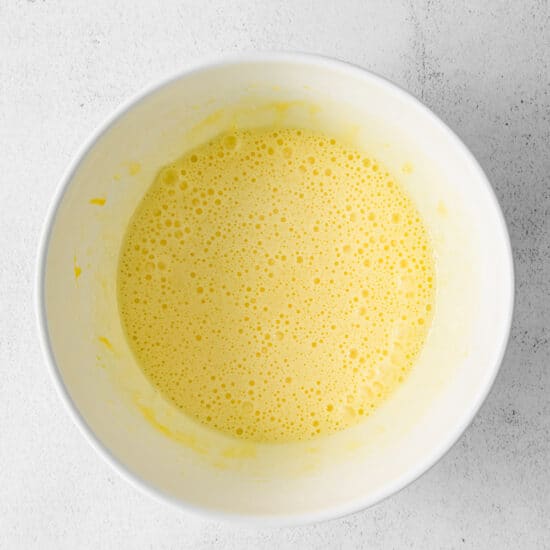 a bowl of yellow liquid on a white surface.