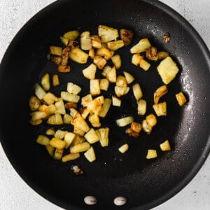 fried potatoes in a frying pan on a white background.