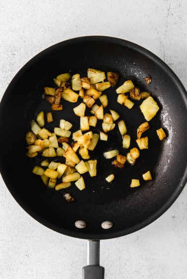 fried potatoes in a frying pan on a white background.