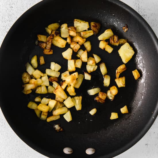 fried potatoes in a frying pan on a white background.