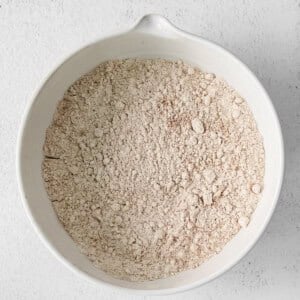 flour in a white bowl on a white surface.