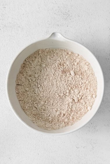 flour in a white bowl on a white surface.