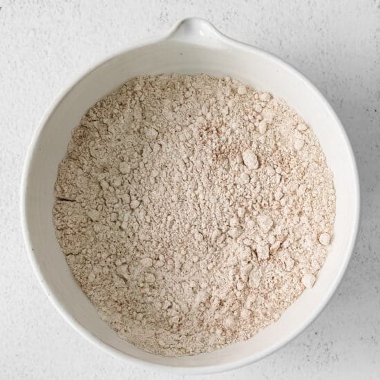 flour in a white bowl on a white surface.