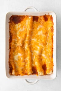 cheesy enchiladas in a white baking dish.