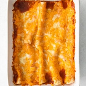 cheesy enchiladas in a white baking dish.