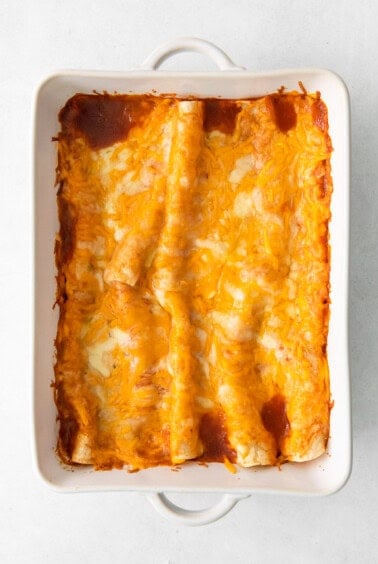 cheesy enchiladas in a white baking dish.