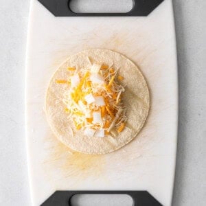 a taco with cheese on a cutting board.