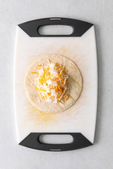 a taco with cheese on a cutting board.