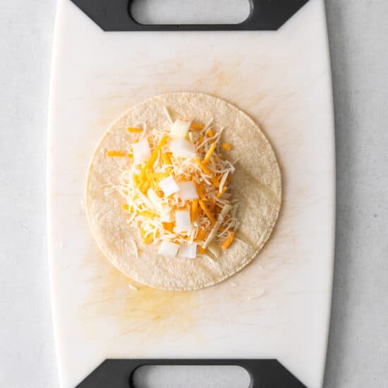 a taco with cheese on a cutting board.