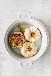 garlic in a white bowl on a white background.