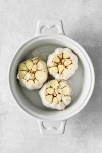 garlic in a white bowl on a grey background.