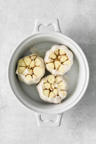garlic in a white bowl on a grey background.
