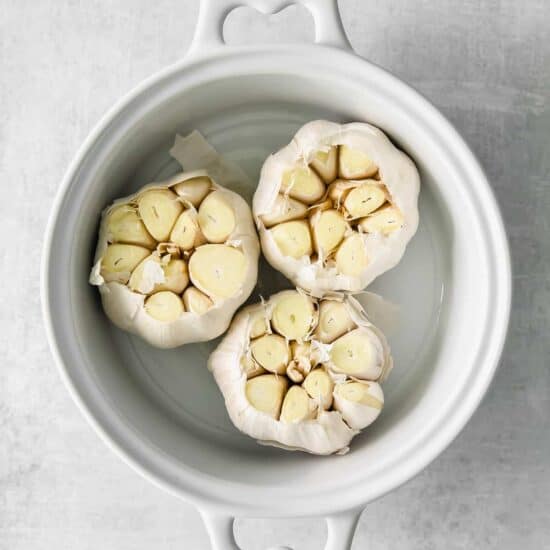 garlic in a white bowl on a grey background.