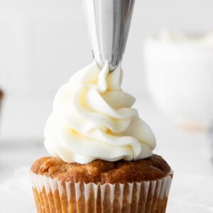 Frosting a cupcake with cream cheese frosting.