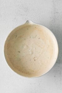 a white bowl with a white sauce on it.