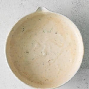 a white bowl with a white sauce on it.