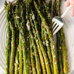 roasted asparagus on a plate with a fork.