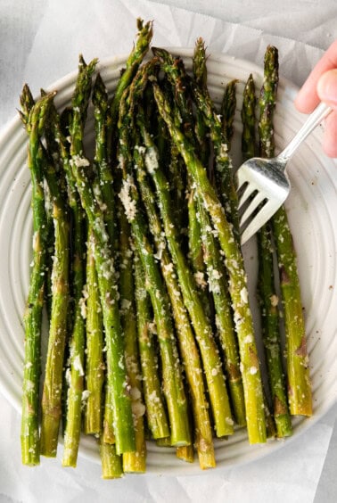 roasted asparagus on a plate with a fork.
