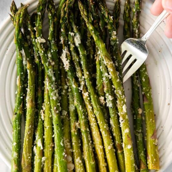 roasted asparagus on a plate with a fork.