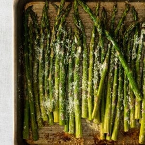 asparagus on a baking sheet with parmesan.